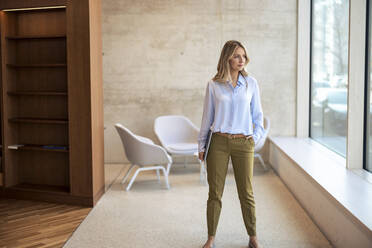 Confident businesswoman with hand in pocket at office - JOSEF12792