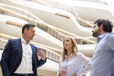 Mature businessman planning strategy with colleagues in lobby - JOSEF12819