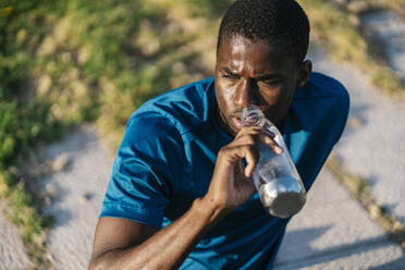 Man drinking water from bottle on sunny day - EGAF02528