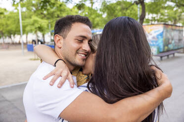 Smiling young man hugging friends at park - WPEF06275