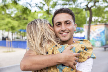 Smiling man hugging girlfriend at park - WPEF06280