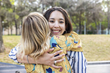 Glückliche junge Frau, die einen Freund im Park umarmt - WPEF06285