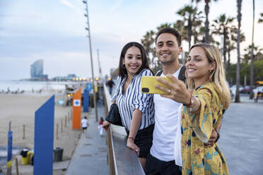Lächelnde Frau macht Selfie mit Freunden an der Promenade - WPEF06316