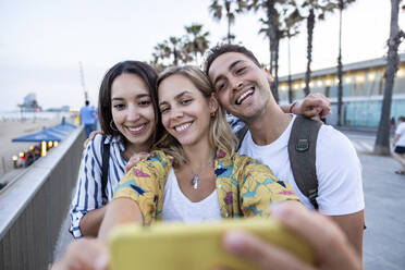 Glückliche junge Frau nimmt Selfie mit Freunden - WPEF06317