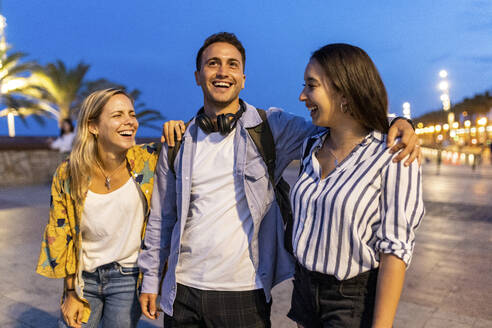 Fröhliche Frauen mit Mann beim Spaziergang an der Promenade - WPEF06324