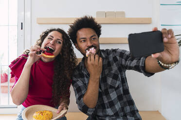 Geschäftsmann mit Selfie mit Geschäftsfrau essen Donut in der Cafeteria - PNAF04463