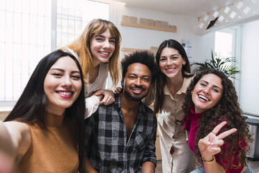 Happy businesswoman taking selfie with colleagues in cafeteria - PNAF04473