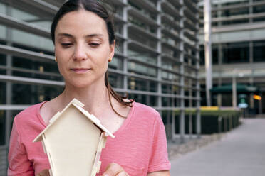 Woman with house model by building - AMWF00357