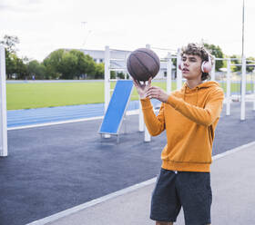 Mann hört Musik über drahtlose Kopfhörer und spielt Basketball - UUF27164