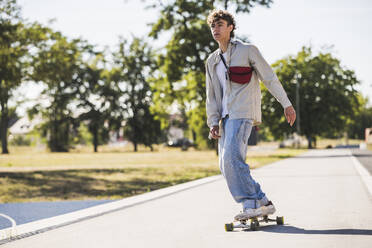 Junger Mann auf dem Skateboard an einem sonnigen Tag - UUF27167