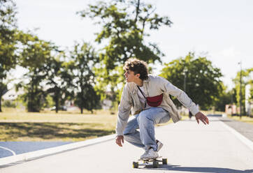 Junger Mann fährt Skateboard auf dem Fußweg - UUF27168
