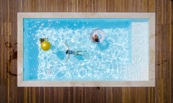 Mother with children enjoying swimming in pool - HMEF01375