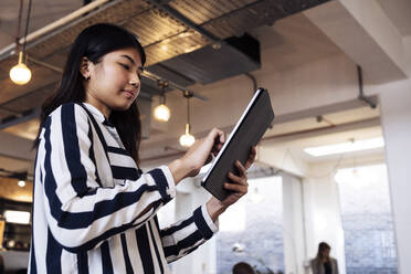 Junge Geschäftsfrau steht in einem Coworking-Büro und benutzt ein digitales Tablet - WESTF24972
