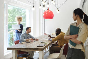 Young woman watching business people working together in modern coworking space - WESTF24991