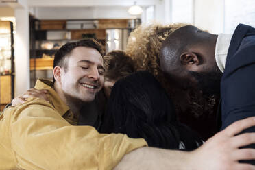 Happy business people hugging in office - WESTF24994