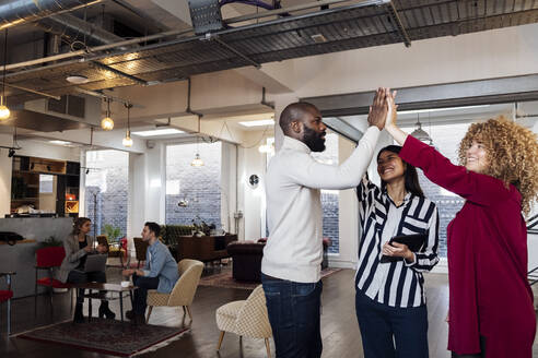 Young businesswomen and colleague high fiving in office - WESTF25025