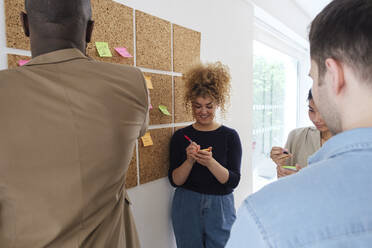 Geschäftsleute, die im Büro stehen und Brainstorming betreiben und Notizen machen - WESTF25037