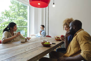 Geschäftsleute beim gemeinsamen gesunden Mittagessen im Personalraum eines modernen Büros - WESTF25047