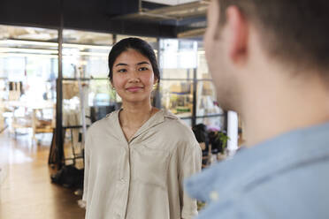 Junge Frau im Gespräch mit einem Kollegen in einem modernen Coworking Space - WESTF25067