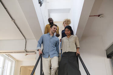 Gruppe von Geschäftsleuten, die eine Treppe in einem modernen Büro hinabsteigen - WESTF25068