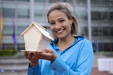 Happy young woman with model house - AMWF00360