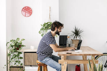 Freiberufler, der an einem Laptop arbeitet, der an einem Schreibtisch im Heimbüro steht - XLGF03053