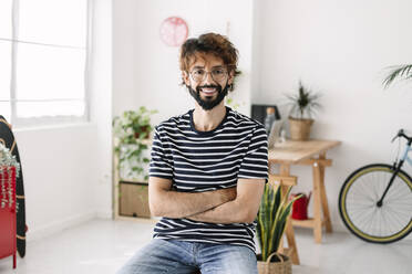 Man sitting with arms crossed in home office - XLGF03058