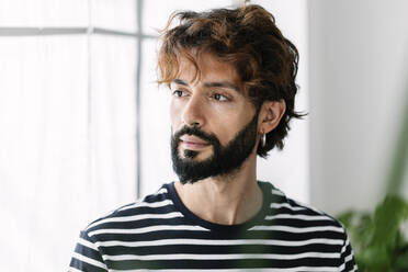 Contemplative man with striped t-shirt at home - XLGF03077