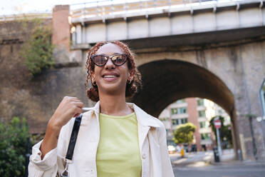 Happy woman with curly hair wearing sunglasses - ASGF02775