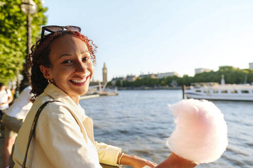 Glückliche Frau mit Zuckerwatte am Ufer der Themse - ASGF02790