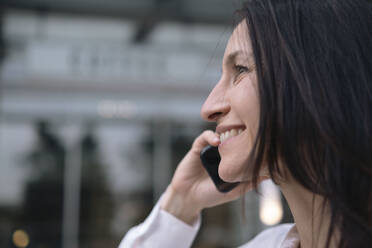 Glückliche Geschäftsfrau, die mit einem Mobiltelefon spricht - AMWF00392