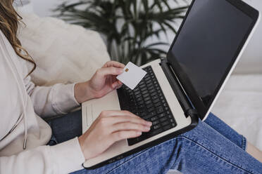 Frau, die mit einer Kreditkarte über einen Laptop bezahlt - EBBF06017