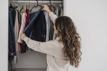 Woman selecting clothes from closet at home - EBBF06026