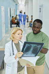 Patient discussing over X-ray image with doctor in hospital corridor - DSHF00537