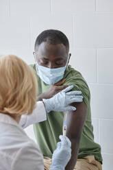 Arzt injiziert in der Klinik den Impfstoff COVID-19 in den Arm eines Patienten - DSHF00560
