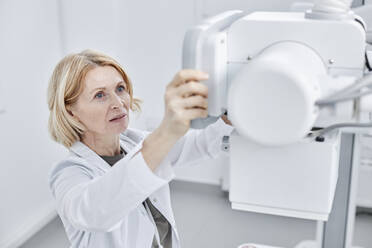 Doctor looking at X-ray machine in clinic - DSHF00568