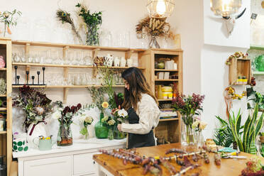 Florist holding flower standing at floral store - MRRF02409