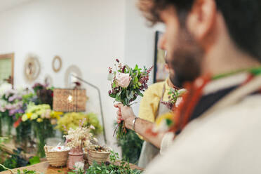 Florist mit Blumenstrauß und Kollege in einem Blumenladen - MRRF02415