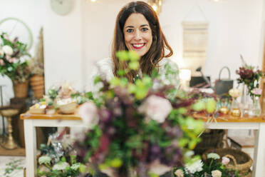 Glückliche Floristin mit Blumenstrauß im Blumenladen - MRRF02419