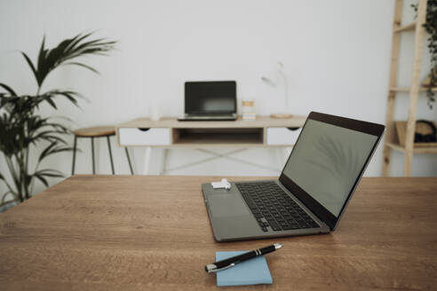 Laptop mit Haftnotiz und Stift auf dem Tisch im Büro - EBBF06052