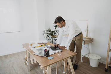 Architect using laptop at desk in office - EBBF06055