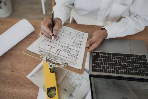 Hände eines Architekten, der einen Bauplan im Büro hält - EBBF06061