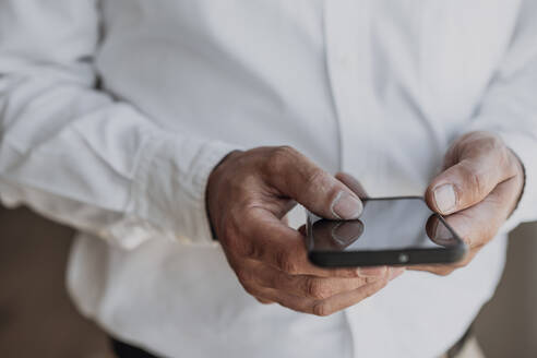 Hände eines Geschäftsmannes, der ein Smartphone benutzt - EBBF06080