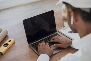 Hands of engineer using laptop at desk - EBBF06098