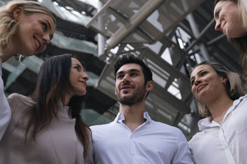 Smiling businessman discussing with colleagues in front of building - AMWF00454