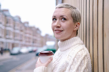 Contemplative woman with reusable cup by wall - AMWF00510