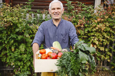 Lächelnder älterer Mann mit frisch geerntetem Gemüse - EYAF02091