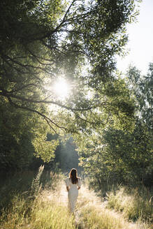 Frau im weißen Kleid geht im Wald spazieren - EYAF02106