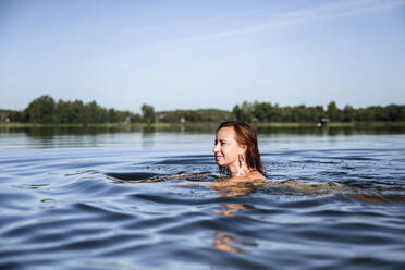 Lächelnde Frau genießt das Schwimmen im See - EYAF02116