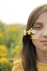 Girl with flowers attached on cheek by adhesive bandage - LESF00015